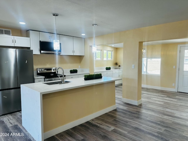 kitchen featuring white cabinets, decorative light fixtures, stainless steel appliances, and a kitchen island with sink