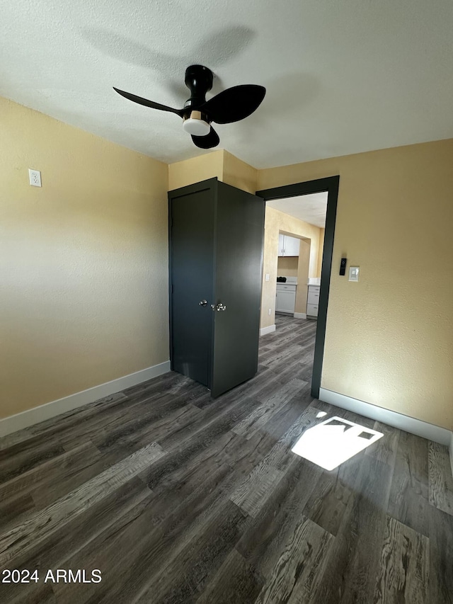 unfurnished bedroom featuring a textured ceiling, dark hardwood / wood-style flooring, a closet, and ceiling fan