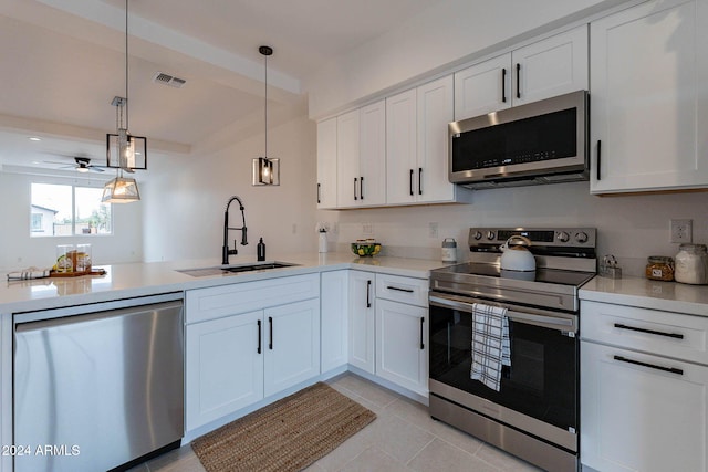 kitchen with appliances with stainless steel finishes, white cabinets, sink, and pendant lighting