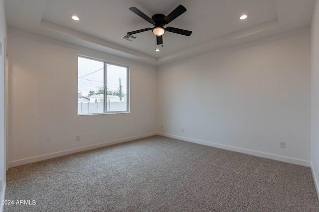 carpeted empty room with a tray ceiling and ceiling fan