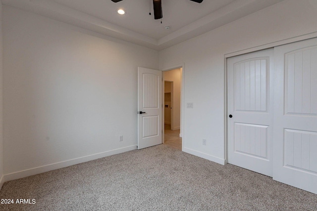 unfurnished bedroom featuring light colored carpet, a closet, and ceiling fan