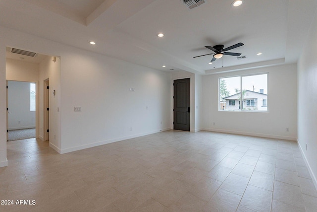 spare room with a tray ceiling and ceiling fan