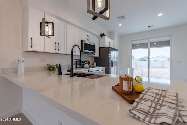 kitchen with appliances with stainless steel finishes, white cabinetry, light stone countertops, and sink