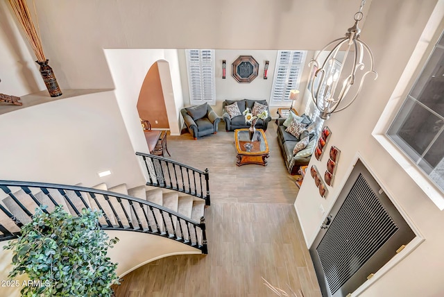 stairway with wood-type flooring and an inviting chandelier