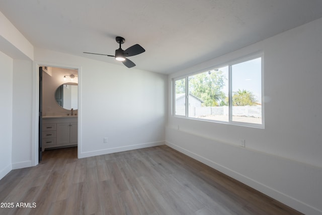 unfurnished bedroom featuring ceiling fan, connected bathroom, sink, and light hardwood / wood-style floors