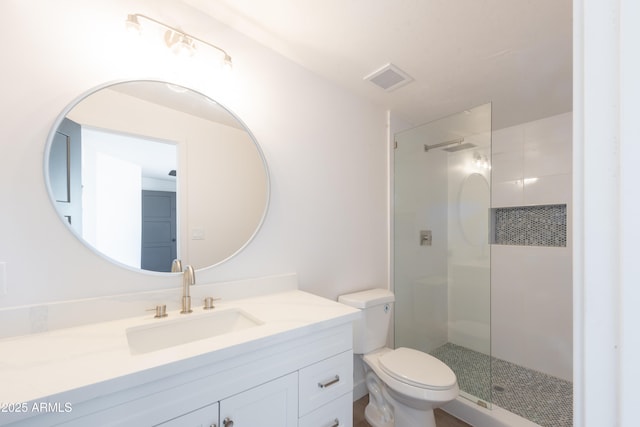 bathroom with vanity, toilet, and a tile shower