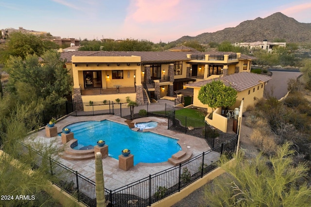 pool at dusk with a mountain view, a patio area, and an in ground hot tub