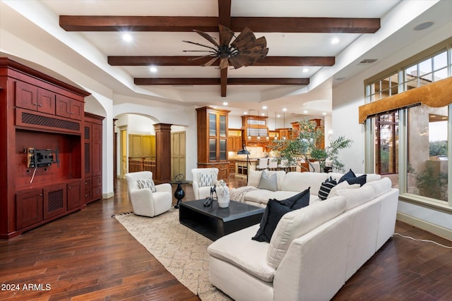 living room featuring beamed ceiling, a healthy amount of sunlight, and dark wood-type flooring