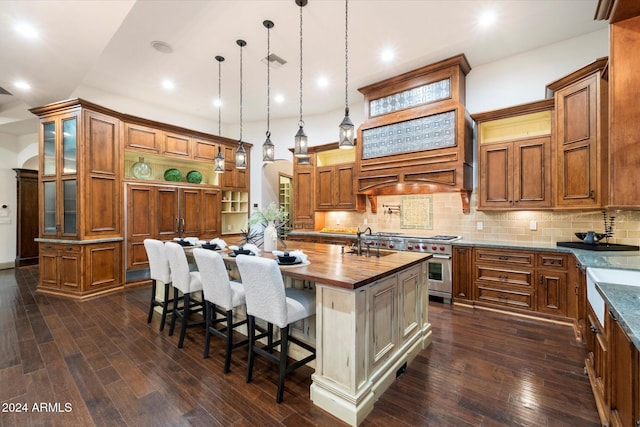 kitchen featuring double oven range, a kitchen island with sink, dark hardwood / wood-style floors, decorative backsplash, and decorative light fixtures