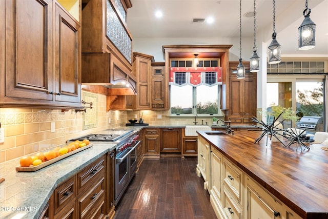 kitchen with sink, dark wood-type flooring, wooden counters, range with two ovens, and decorative light fixtures