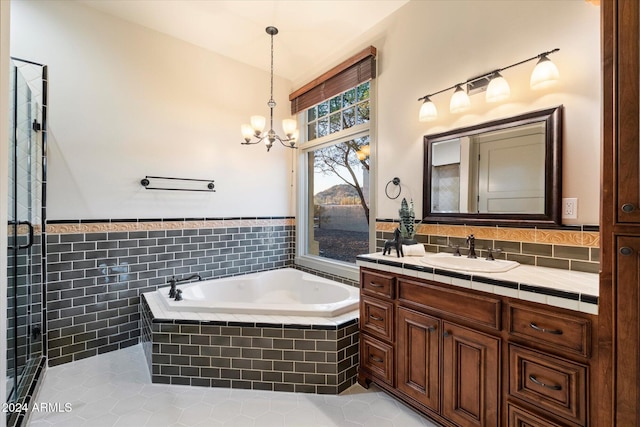 bathroom with tile patterned floors, vanity, tiled tub, an inviting chandelier, and tile walls