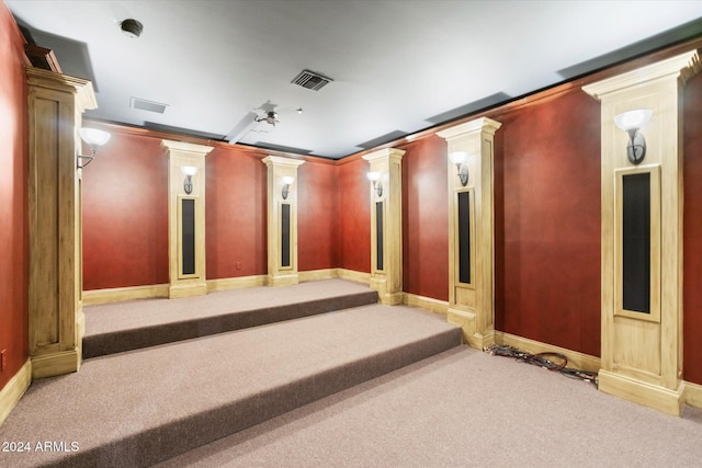 cinema room with decorative columns, light carpet, ceiling fan, and ornamental molding