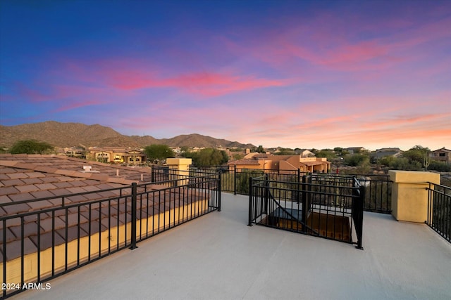 patio terrace at dusk featuring a mountain view and a balcony