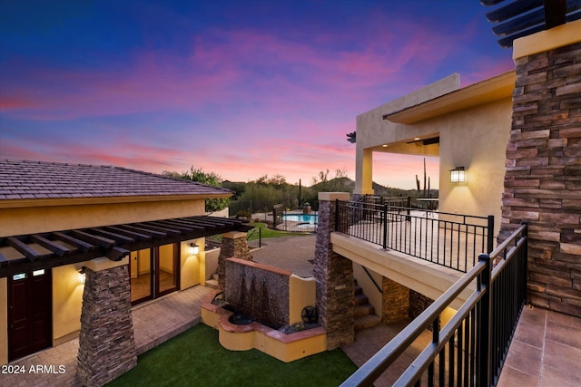 patio terrace at dusk with a fenced in pool