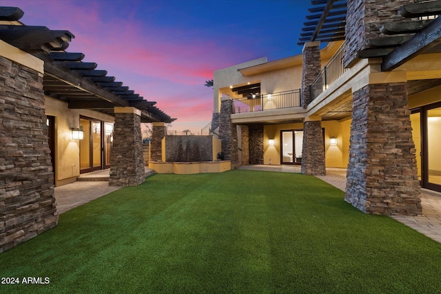 yard at dusk featuring a patio, a balcony, and a pergola