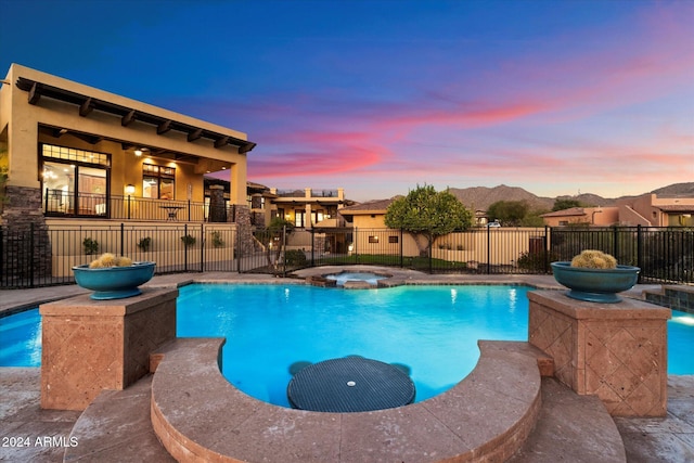 pool at dusk with an in ground hot tub