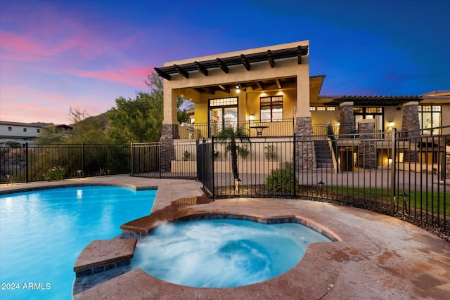 pool at dusk with an in ground hot tub