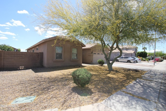 view of front of home featuring driveway, a garage, stucco siding, and fence