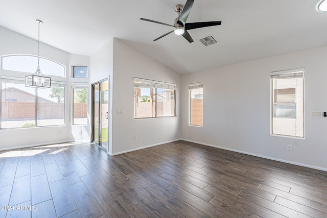 empty room with ceiling fan with notable chandelier, a wealth of natural light, lofted ceiling, and dark hardwood / wood-style floors