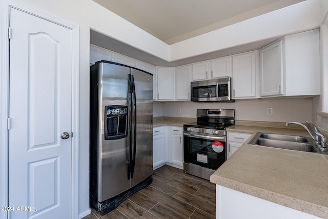 kitchen featuring appliances with stainless steel finishes, white cabinetry, sink, and dark hardwood / wood-style flooring