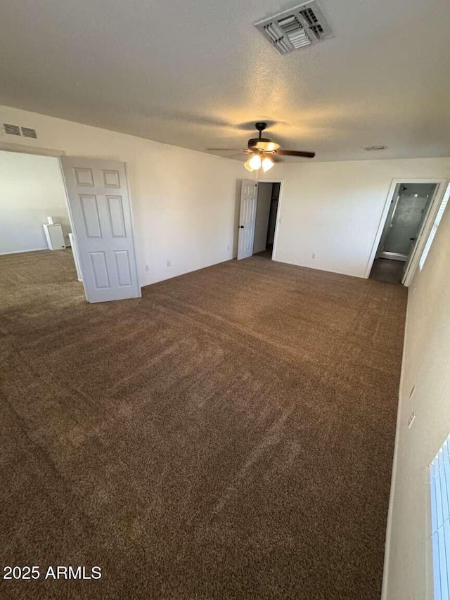 unfurnished room with a textured ceiling, ceiling fan, and dark colored carpet