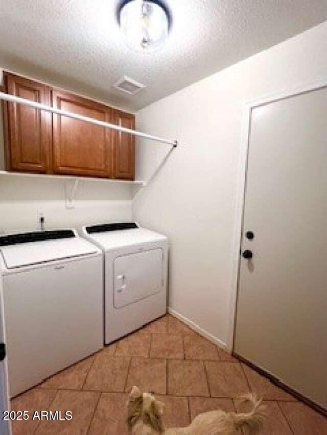 washroom featuring washer and clothes dryer, a textured ceiling, and cabinets