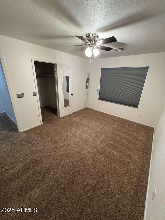 unfurnished bedroom with a textured ceiling, dark colored carpet, ceiling fan, and a closet