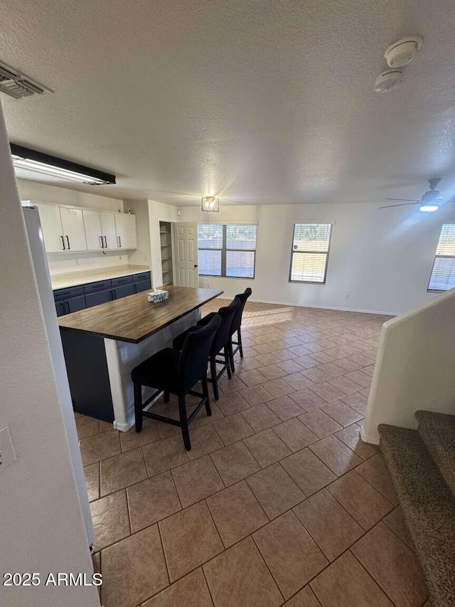 dining room featuring a textured ceiling, ceiling fan, and light tile patterned floors