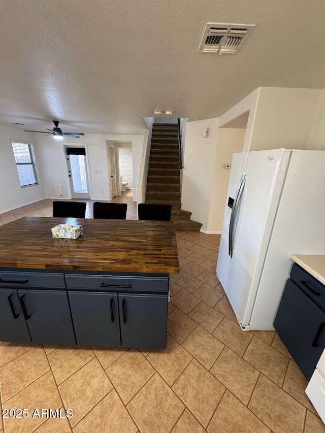 kitchen with white refrigerator with ice dispenser, a textured ceiling, butcher block counters, and ceiling fan