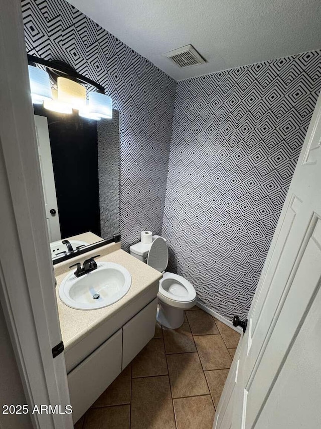 bathroom featuring toilet, tile patterned flooring, a textured ceiling, and vanity