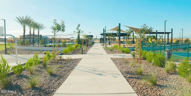 view of community featuring a tennis court, playground community, and fence