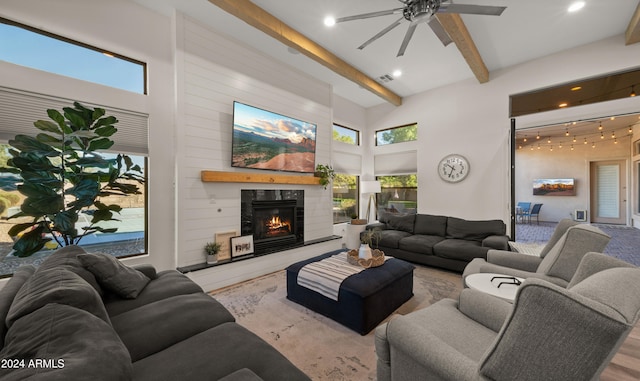 living room with a high ceiling, beamed ceiling, a tiled fireplace, and visible vents