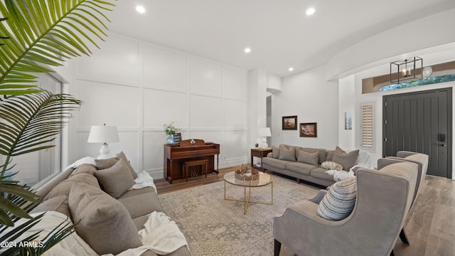 living area with recessed lighting, wood finished floors, and a decorative wall