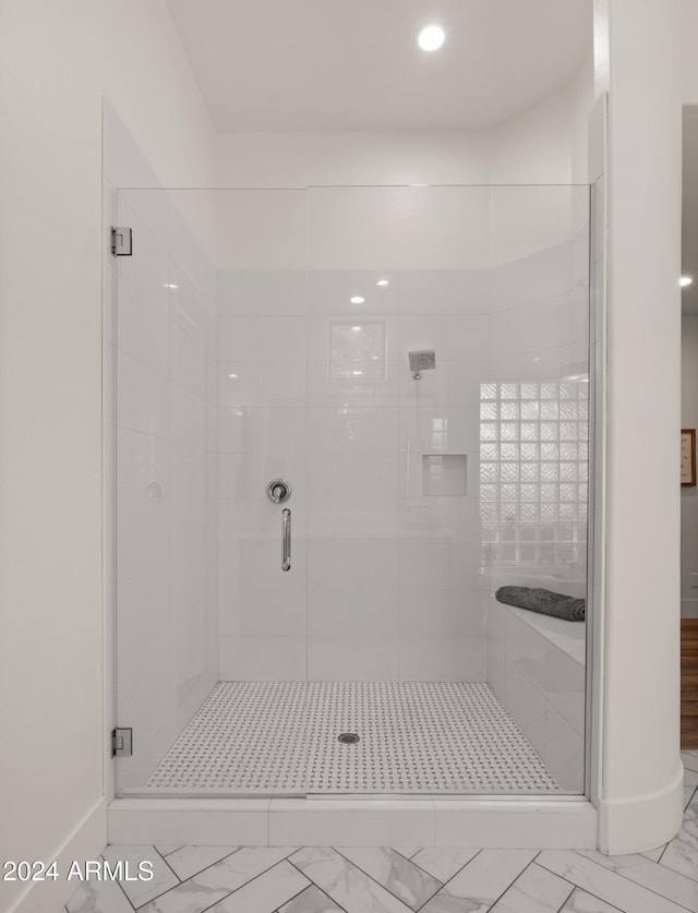 full bath featuring marble finish floor, a stall shower, and baseboards