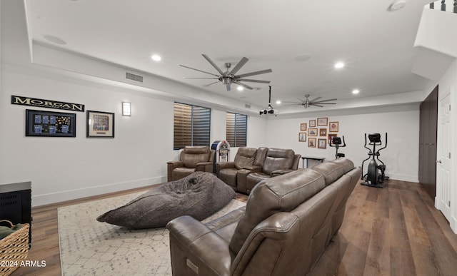 cinema room with a tray ceiling, visible vents, dark wood finished floors, and recessed lighting