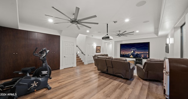 cinema featuring ceiling fan, recessed lighting, a raised ceiling, and light wood-style floors