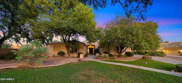 view of front of property with stucco siding, a tile roof, and a yard