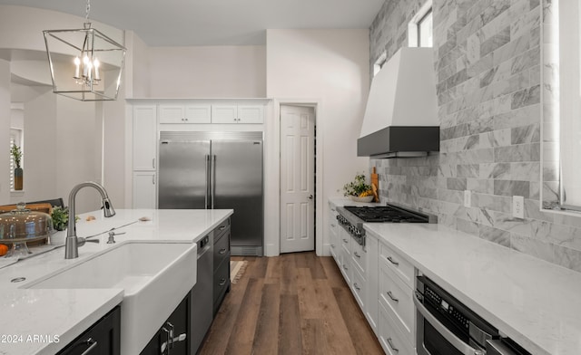 kitchen with premium range hood, a sink, white cabinets, appliances with stainless steel finishes, and tasteful backsplash