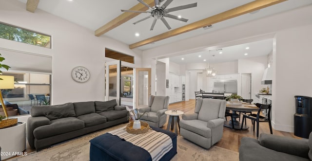 living room featuring ceiling fan, beamed ceiling, a high ceiling, and light wood-type flooring