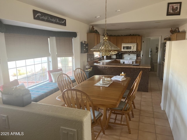 dining room featuring light tile patterned floors, vaulted ceiling, and sink