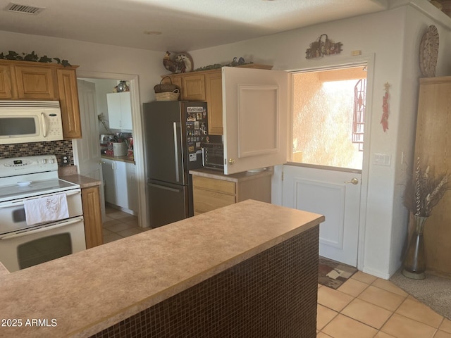 kitchen featuring tasteful backsplash, white appliances, and light tile patterned flooring