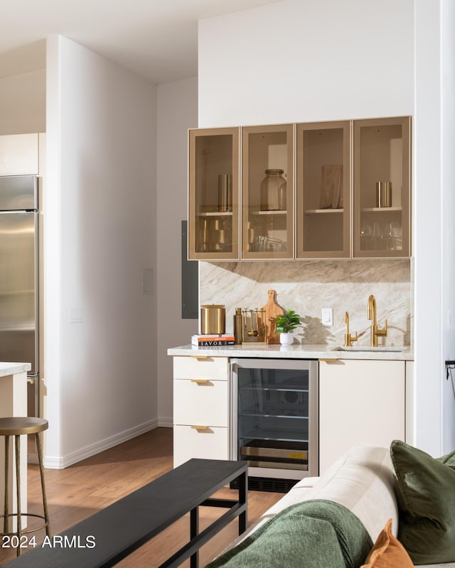 bar with a sink, decorative backsplash, wine cooler, and stainless steel built in fridge