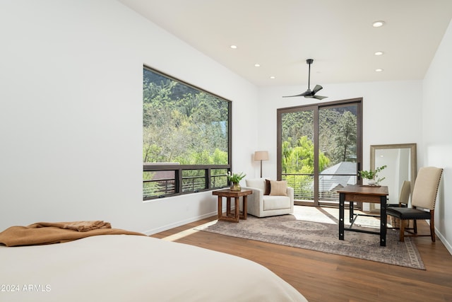 bedroom with recessed lighting, wood finished floors, baseboards, and access to outside