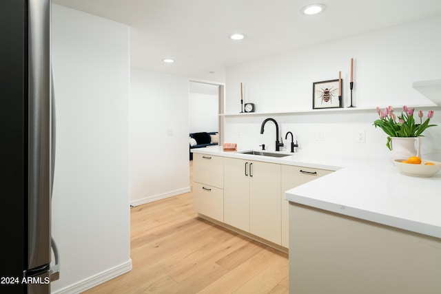 kitchen featuring baseboards, recessed lighting, a sink, light countertops, and light wood-style floors