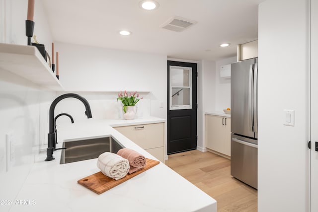 kitchen with light countertops, visible vents, freestanding refrigerator, and a sink