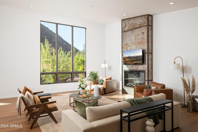 living room featuring recessed lighting, a fireplace, baseboards, and wood finished floors