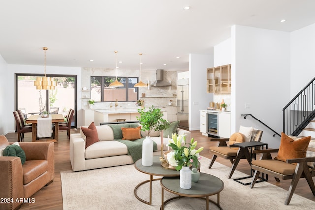 living area with recessed lighting, wood finished floors, beverage cooler, and stairs