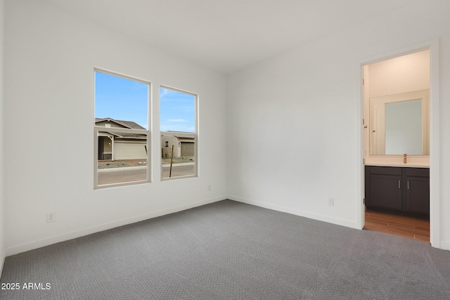 unfurnished bedroom with ensuite bath and carpet floors