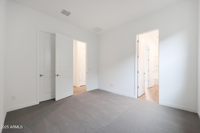 unfurnished bedroom with light carpet and connected bathroom