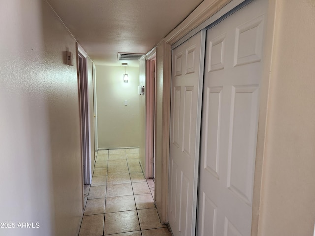 hall featuring light tile patterned floors, visible vents, and a textured ceiling